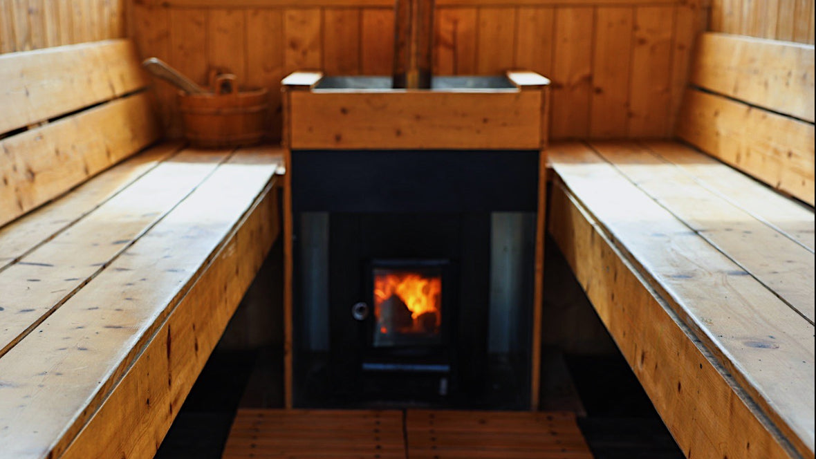 Wooden sauna interior with benches and a fire burning in the stove.